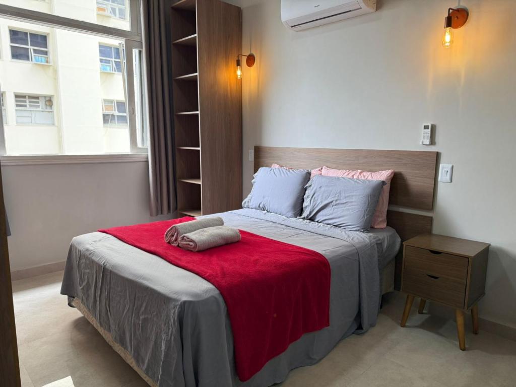 a bedroom with a bed with a red blanket at Flat Centro Rio Av Presidente Vargas x Uruguaiana - Vista panorâmica do Cristo & Metrô in Rio de Janeiro