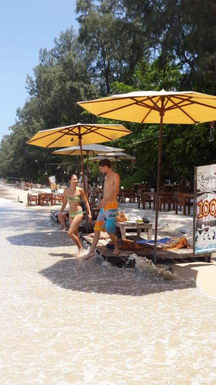 a group of people walking on the beach under umbrellas at JJ Beach Resort & JJ Seafood in Ko Phayam
