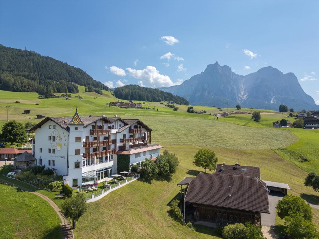 Una vista aérea de un hotel en un campo con montañas. en Parc Hotel Tyrol, en Castelrotto