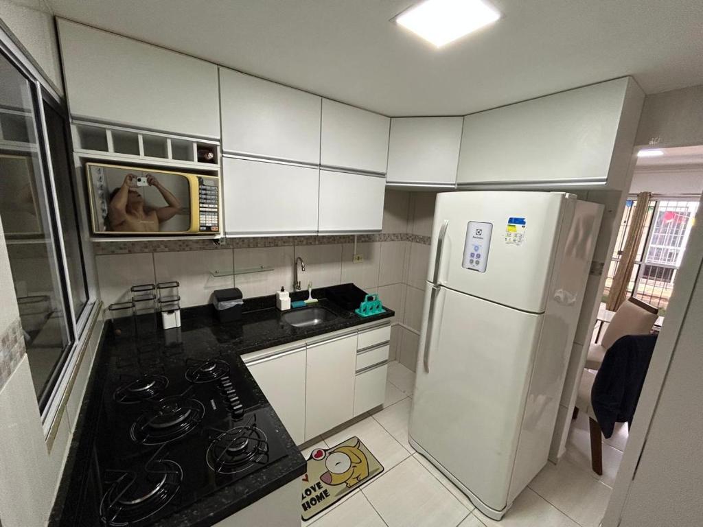 a kitchen with a white refrigerator and a person taking a picture at Flat Perfeito para descansar a 400 metros da praia in Paulista