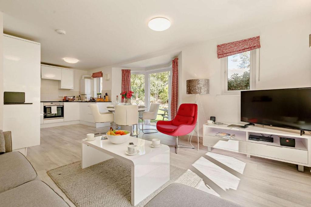 a living room with a large television and a red chair at Sennen - St Ives in Carbis Bay