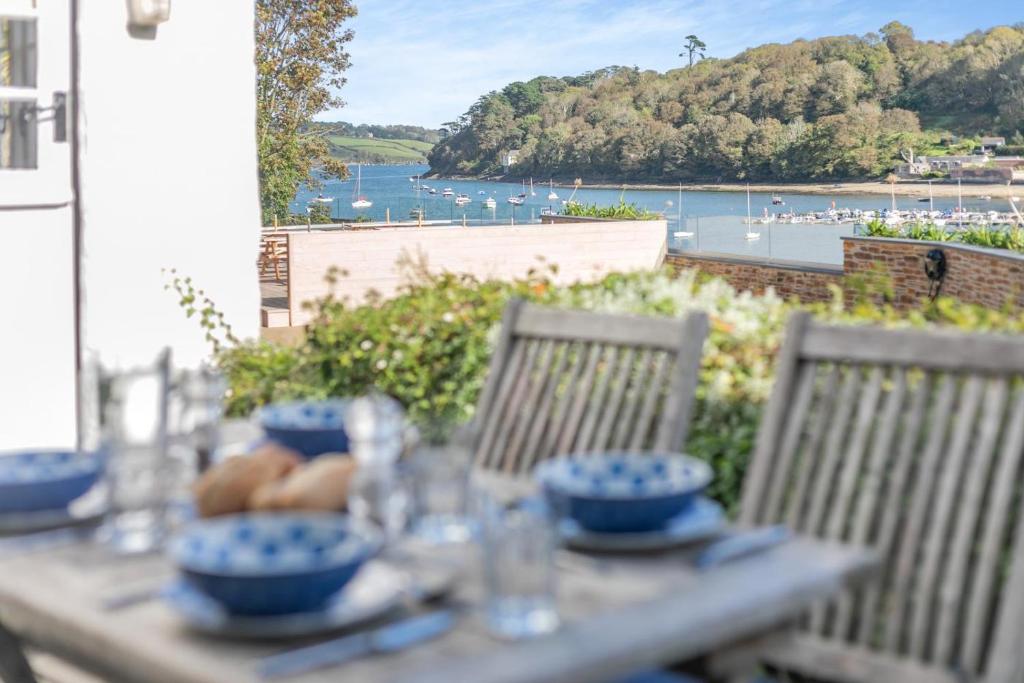une table avec de la vaisselle bleue dessus avec vue sur l'eau dans l'établissement Popigale Cottage, à Helford