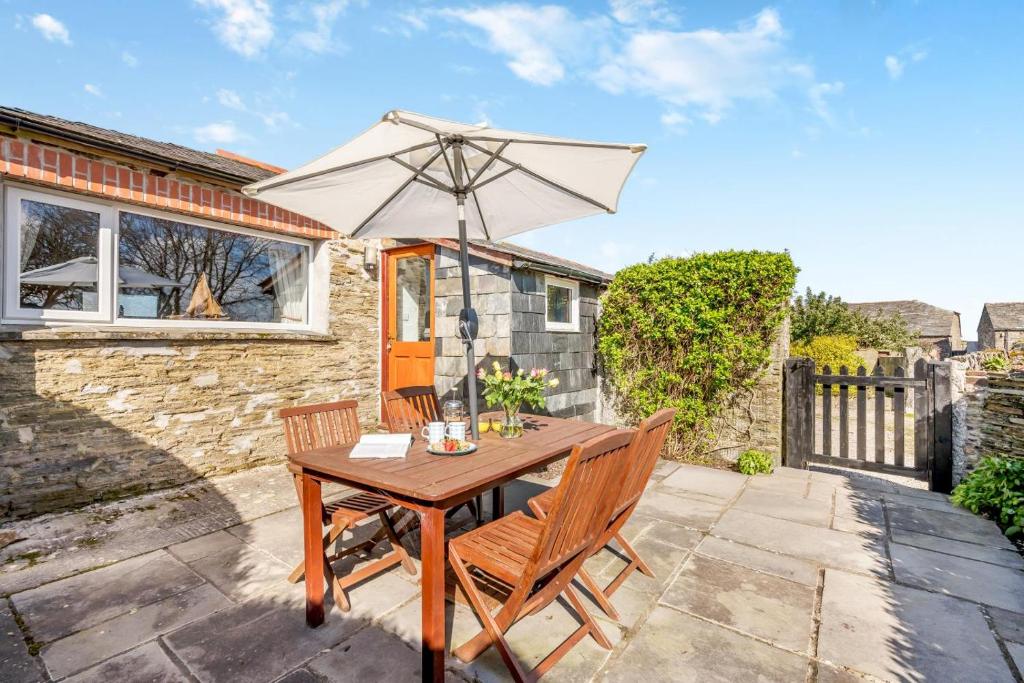 a wooden table with an umbrella on a patio at Wren Cottage in St Merryn