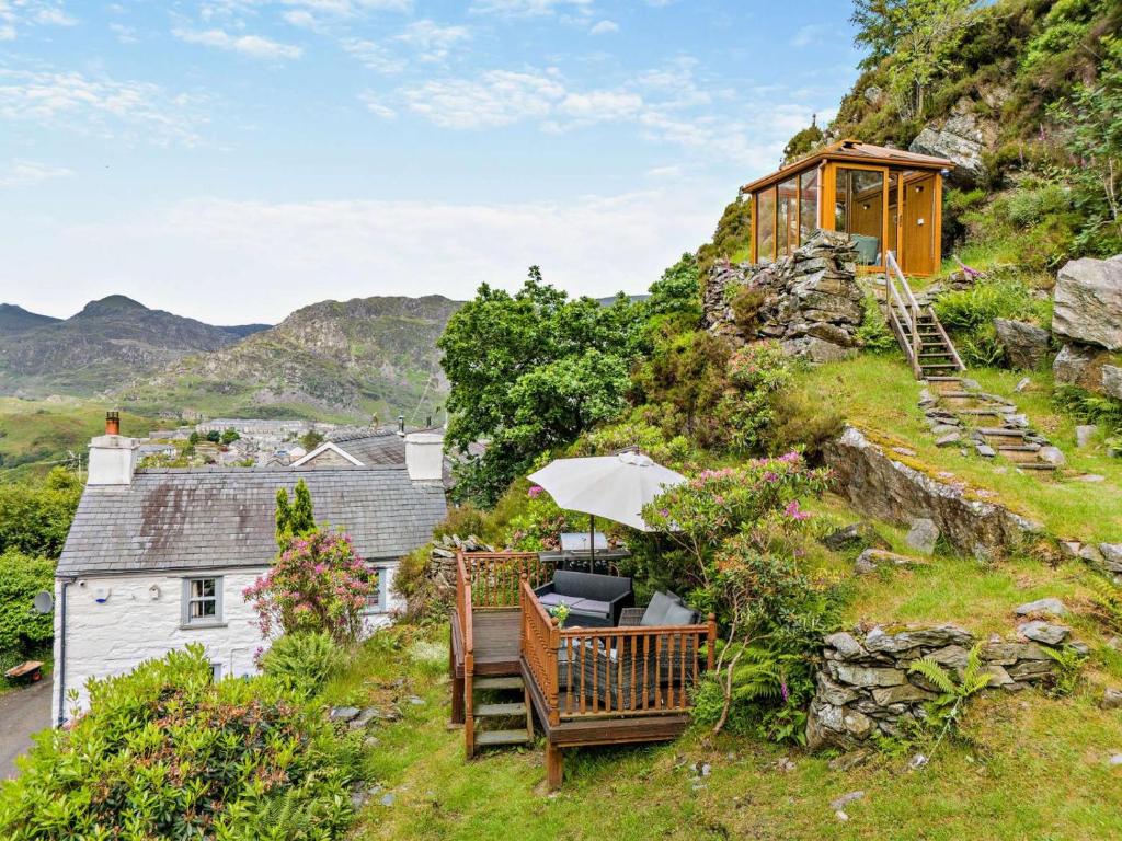 a house on the side of a hill with a bench and an umbrella at Cascades Cottage in Blaenau-Ffestiniog