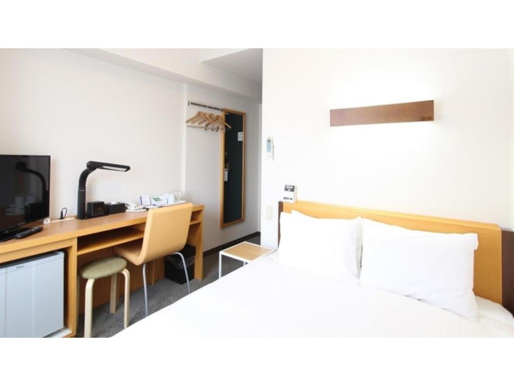 a hotel room with a bed and a desk at Smile Hotel Sakurambo Higashine - Vacation STAY 92763v in Higashine