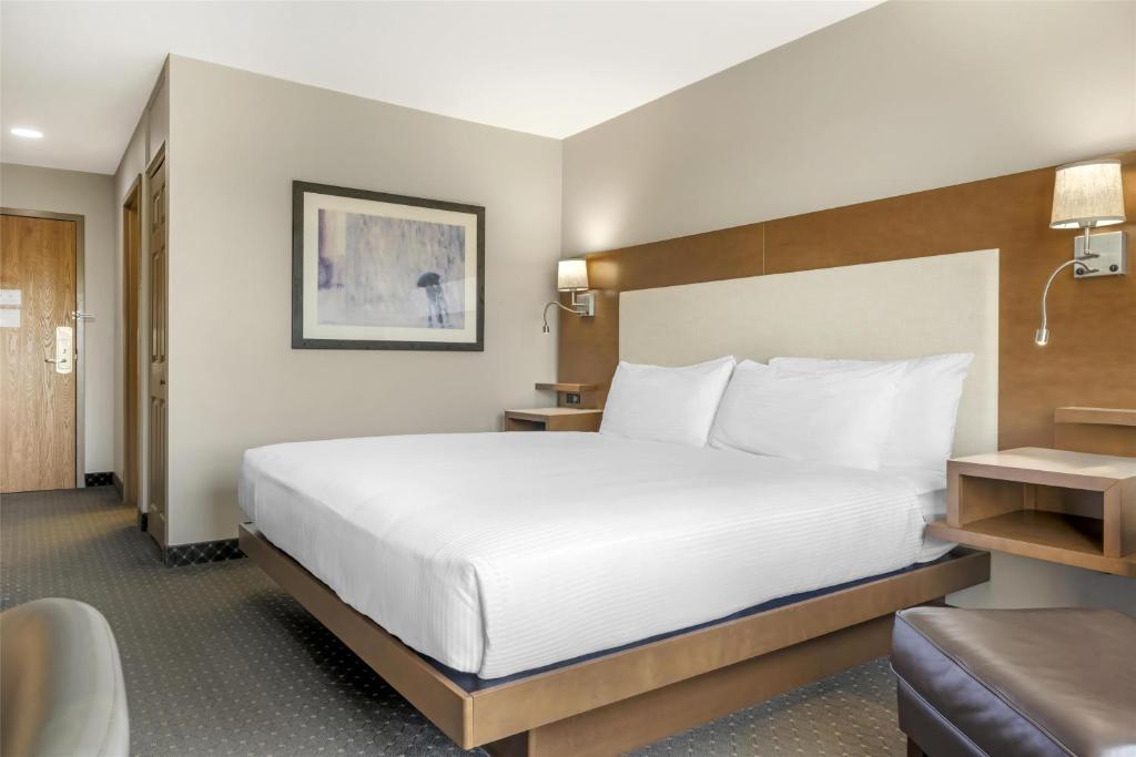 a hotel room with a large bed and a chair at Best Western Plus Woodstock Hotel Conference Centre in Woodstock