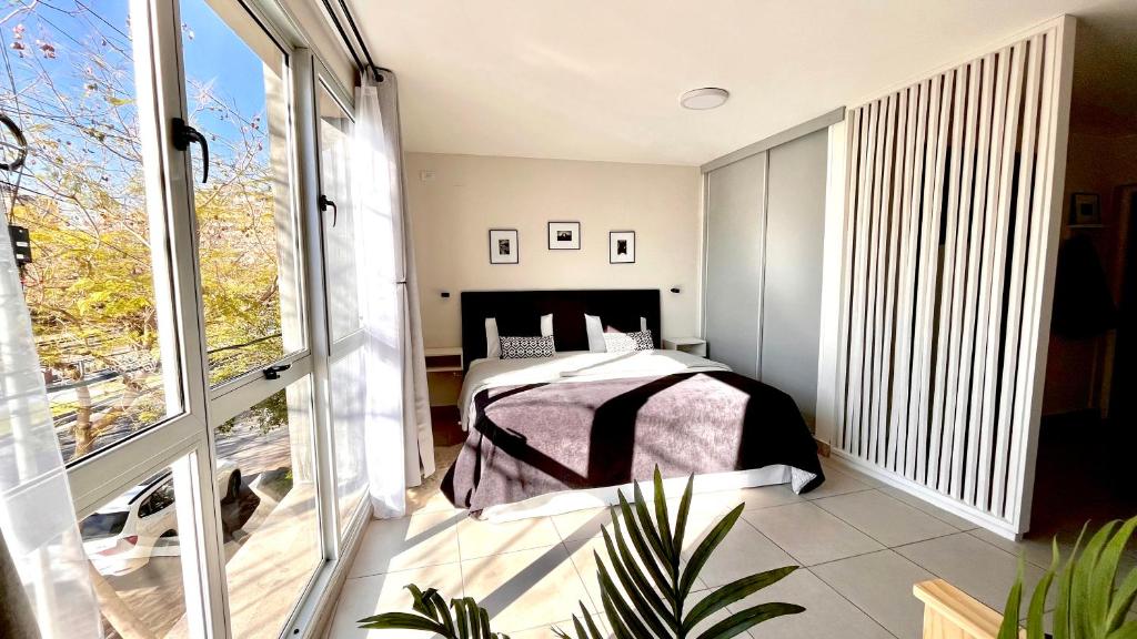 a bedroom with a bed and a large window at Studio Conexión Mendoza moderno céntrico Wifi alta velocidad y a pasos del Parque Gral San Martín y Aristides Villanueva in Godoy Cruz