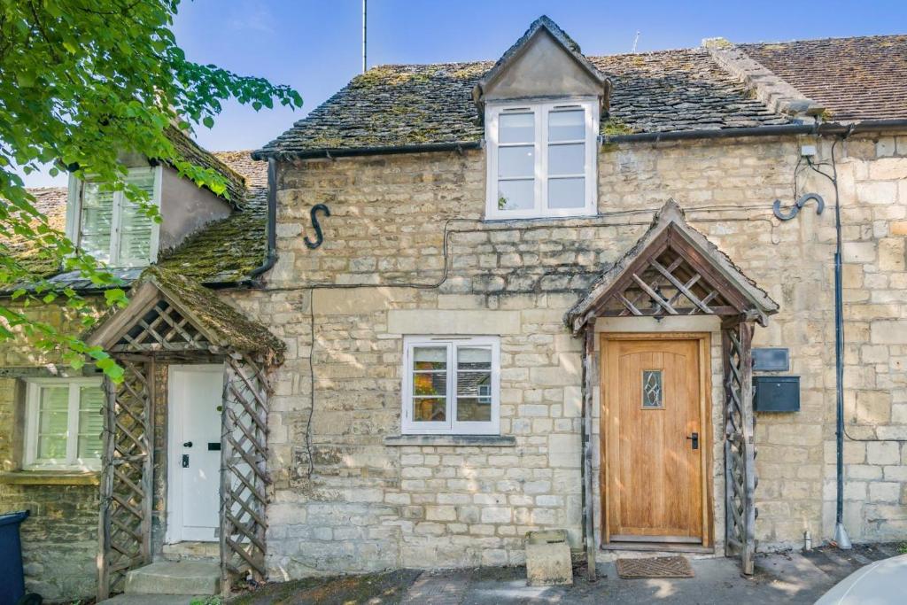 an old stone house with a wooden door at The Cottage - Vineyard Street in Winchcombe