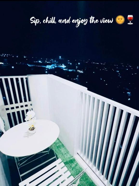 a white table and chair on a balcony at night at Reflective Woodscape- 1 Bedroom with Balcony in Bacolod