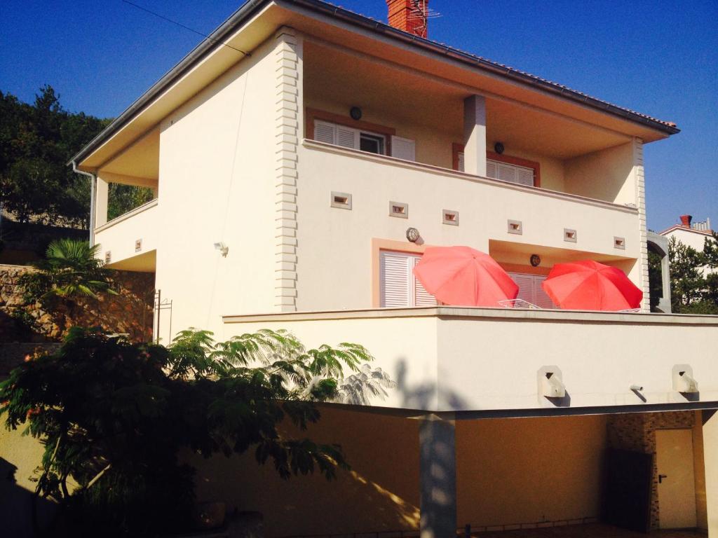 two red umbrellas on the balcony of a house at Apartment Enna in Novi Vinodolski