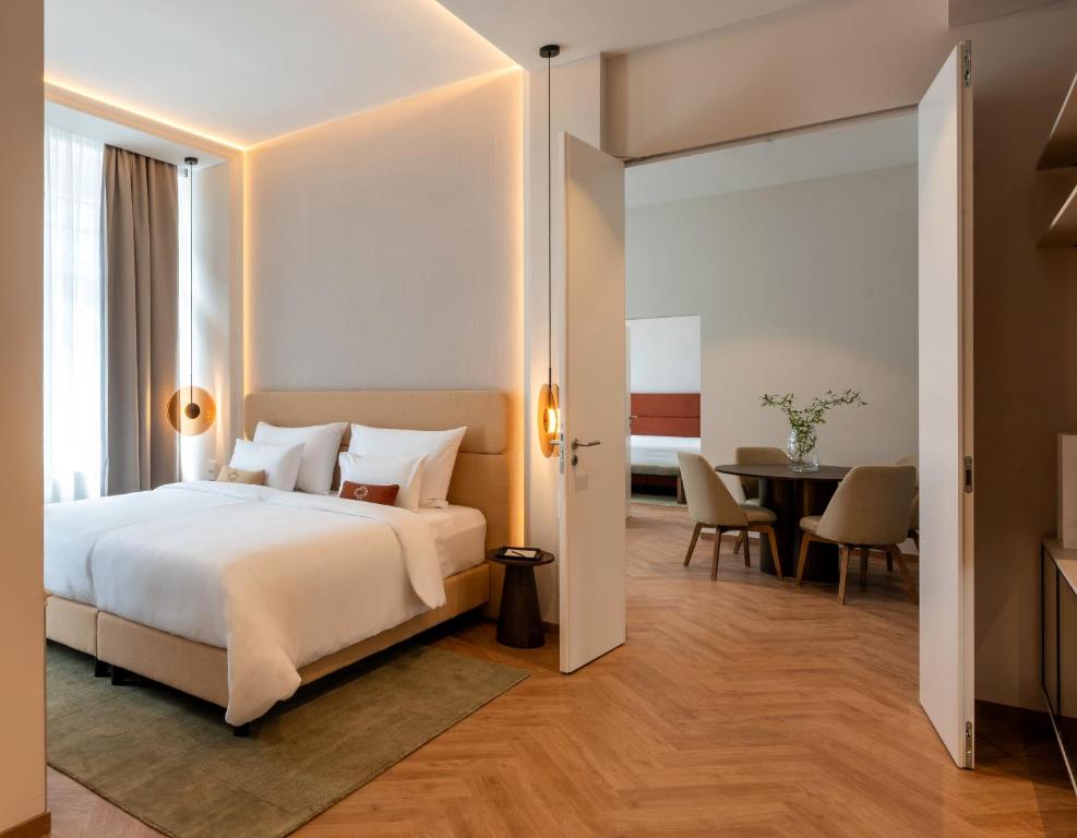 a bedroom with a white bed and a table at LOVIS Suites Vienna in Vienna