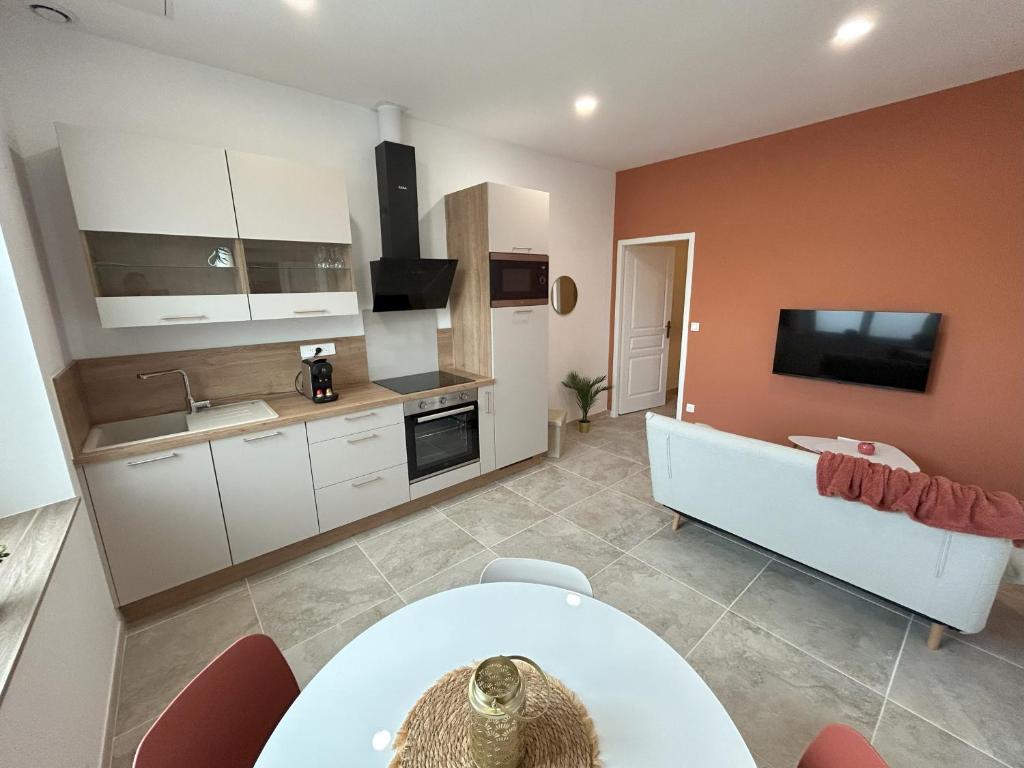 eine Küche mit weißen Schränken und einem TV an der Wand in der Unterkunft Bel appart moderne et climatisé "PAUL" in Alès