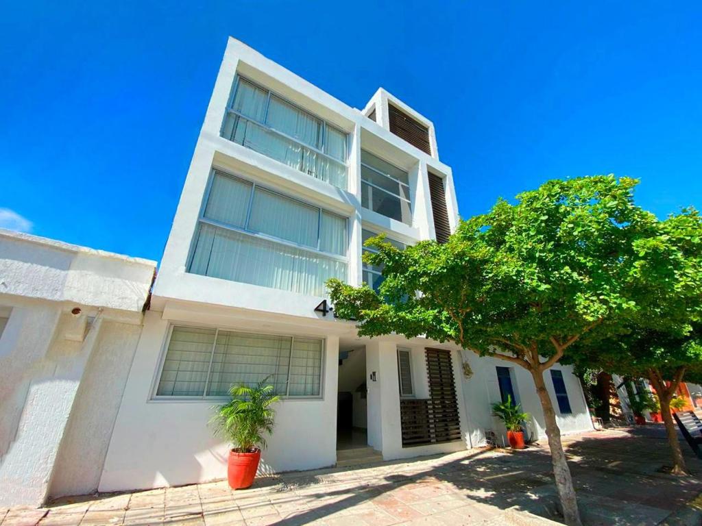 une maison blanche avec un arbre devant dans l'établissement Apartamentos 438, à Ríohacha