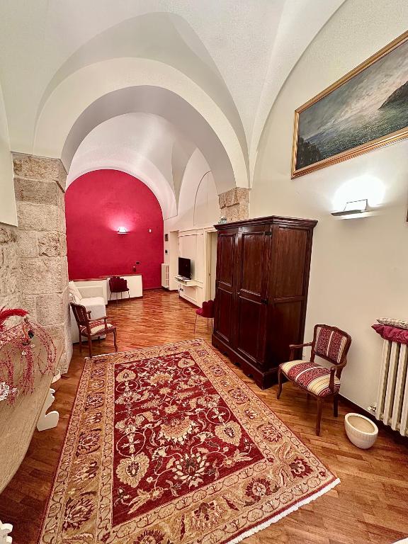 a living room with a rug and a red wall at Suite Santa Caterina in Altamura