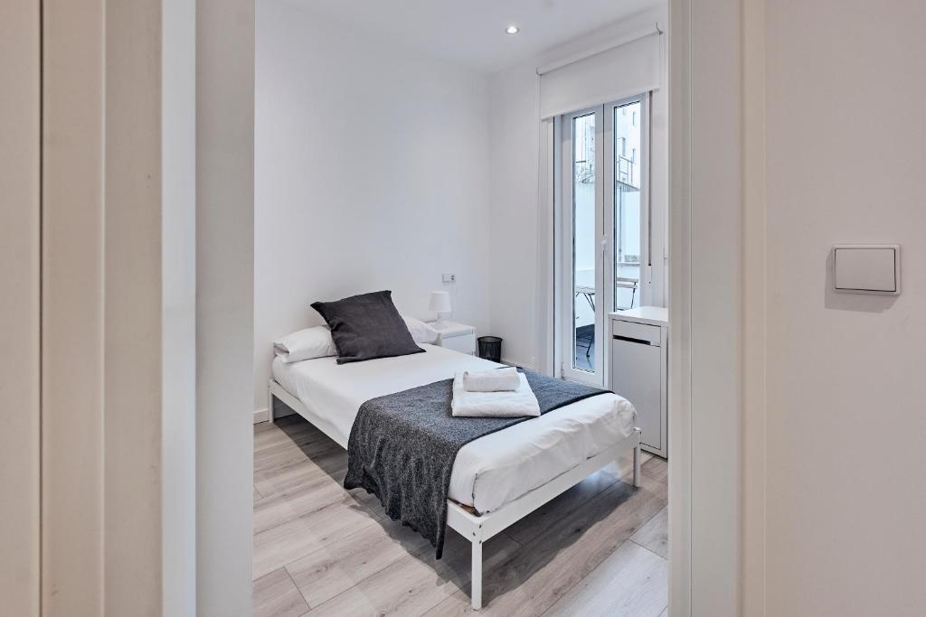 a white bedroom with a bed and a window at San vicente in A Coruña