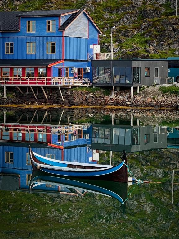 a boat sitting in the water in front of a house at Arran Nordkapp in Honningsvåg