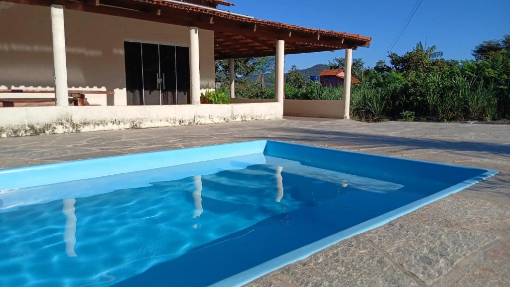 a blue swimming pool in front of a house at Paraíso do Sossego Pirenópolis in Pirenópolis