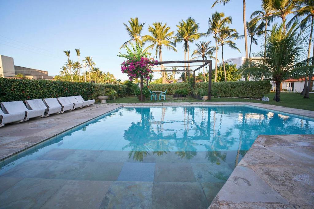 a swimming pool with chairs and palm trees at Casa com Piscina, Churrasqueira e WiFi Cumbuco in Cumbuco