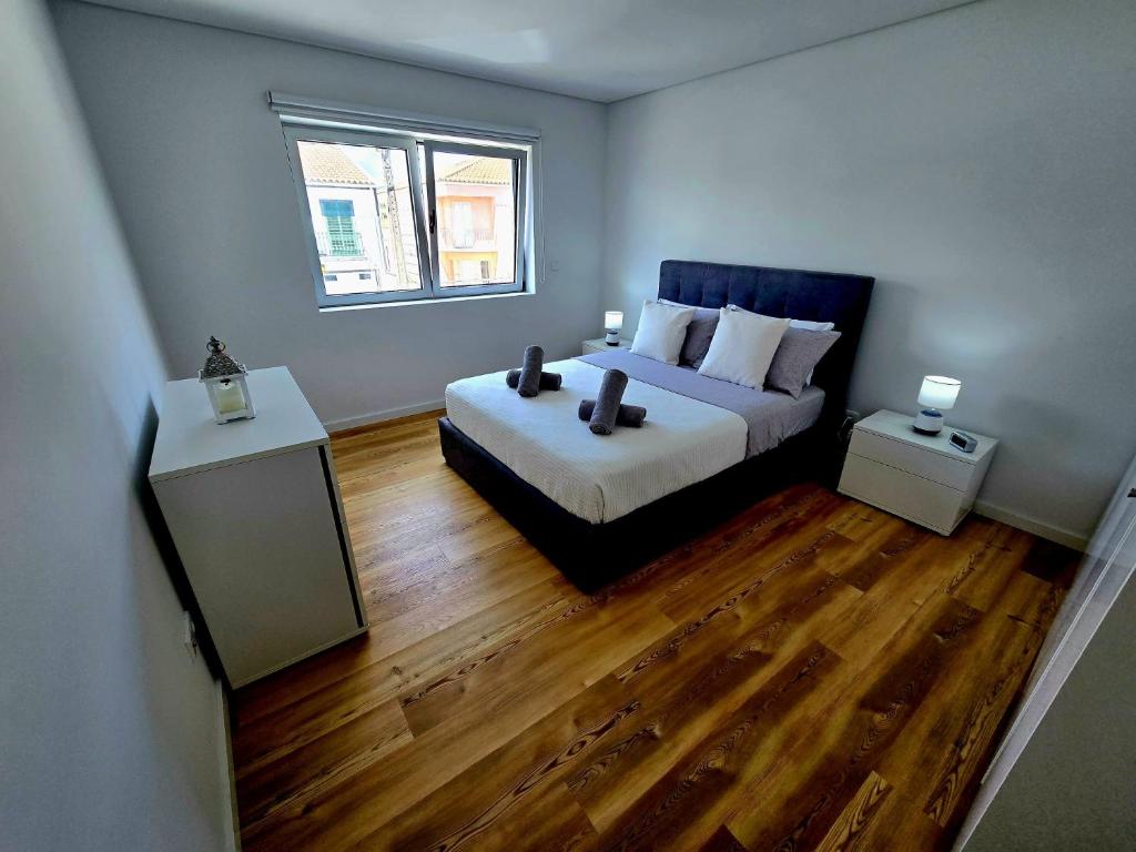 a bedroom with a bed with wooden floors and a window at Lagoa Nest in Lagoa