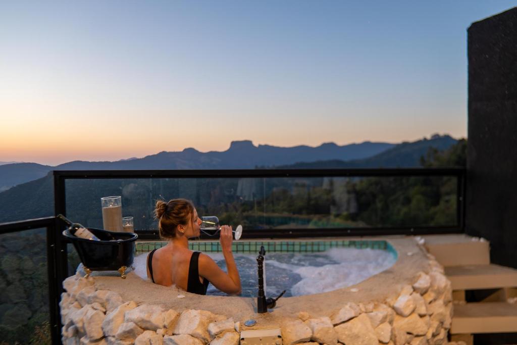 a woman taking a picture in a jacuzzi tub at Chalé Boutique - Spa - Sauna seca , Jacuzzi , Rede suspensa in Campos do Jordão
