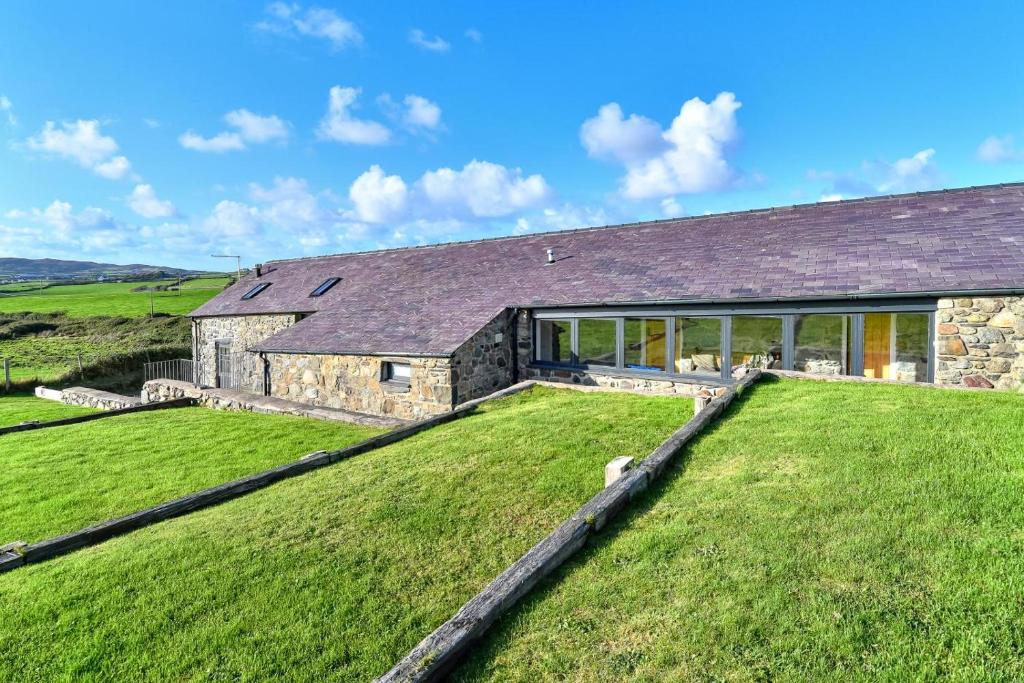 an image of a stone house with a large yard at Geufron Barn in Aberdaron
