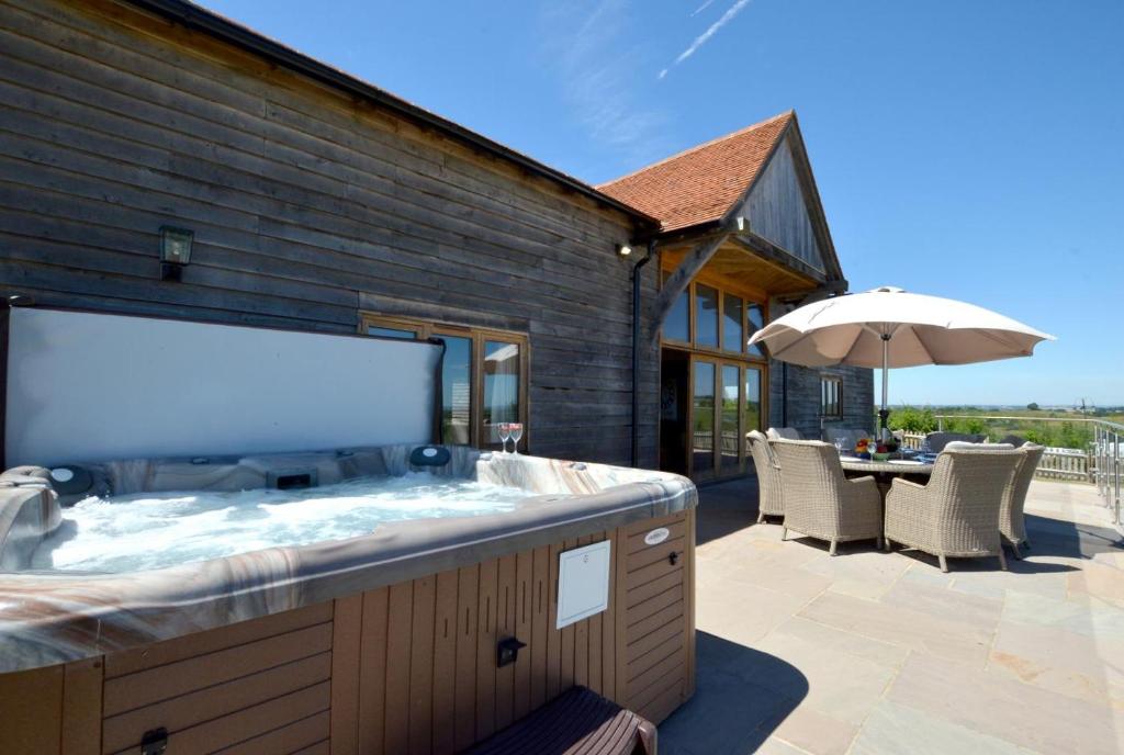 a large tub in a patio with a table and an umbrella at Churchlands Barn in Stone