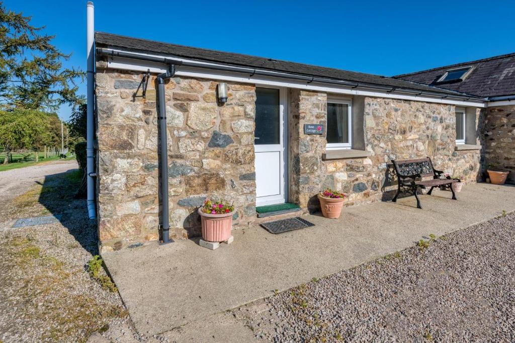 a stone house with a bench in front of it at Rose Cottage in Llanbedrog
