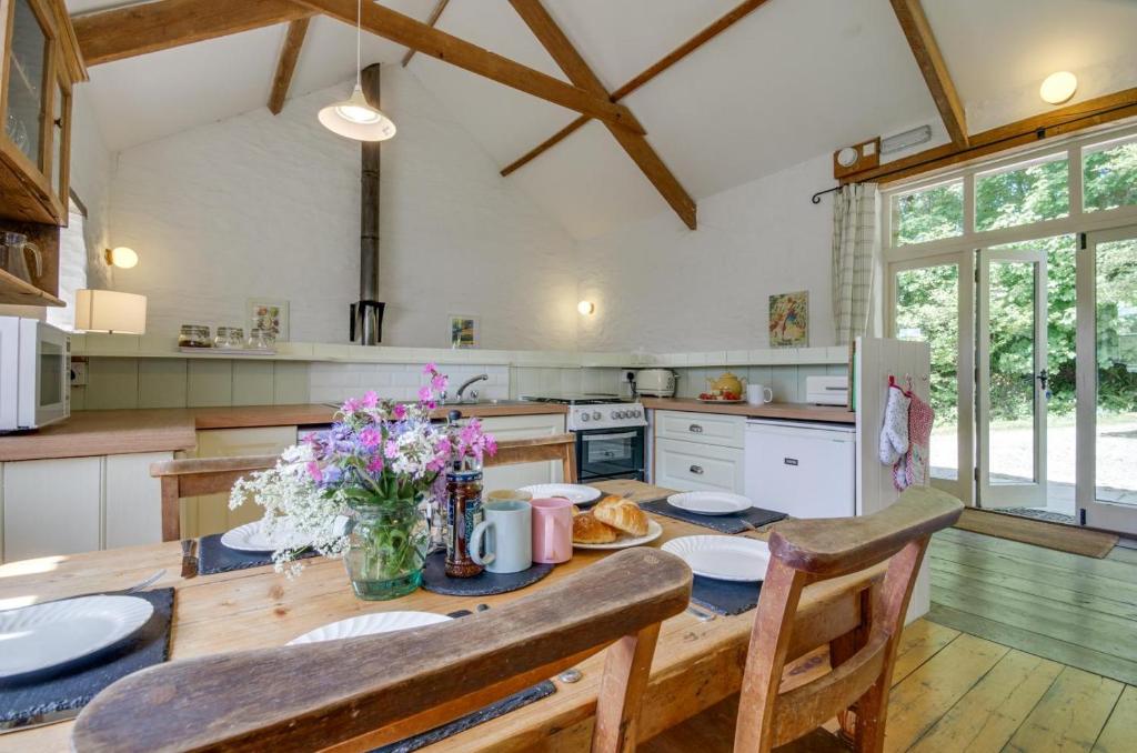 een keuken met een houten tafel met bloemen erop bij Mole Cottage in Parracombe