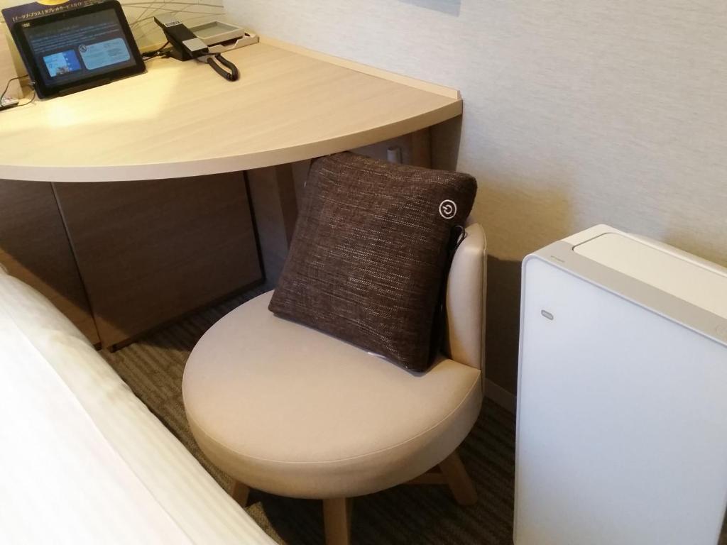 a desk with a chair and a table with a laptop at Meitetsu Inn Hamamatsucho in Tokyo