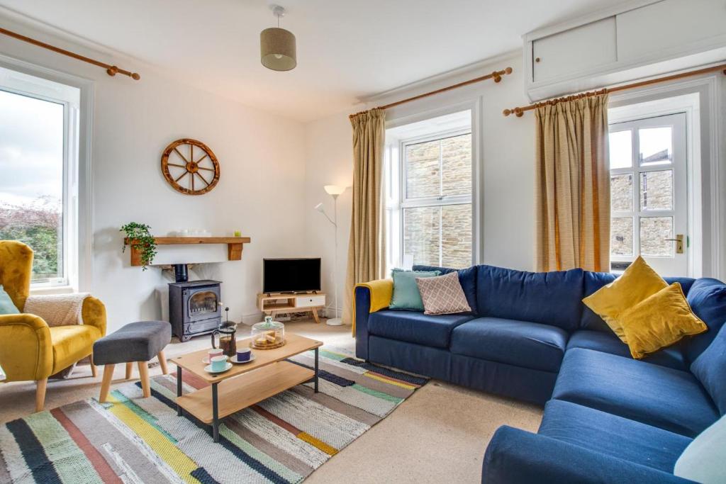 a living room with a blue couch and chairs at 1 Rose Cottage in Hawes