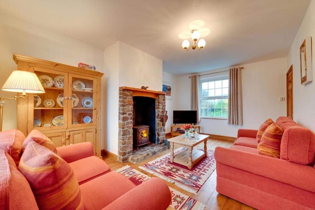 a living room with two red couches and a fireplace at Coastguard Cottage in Blagberry