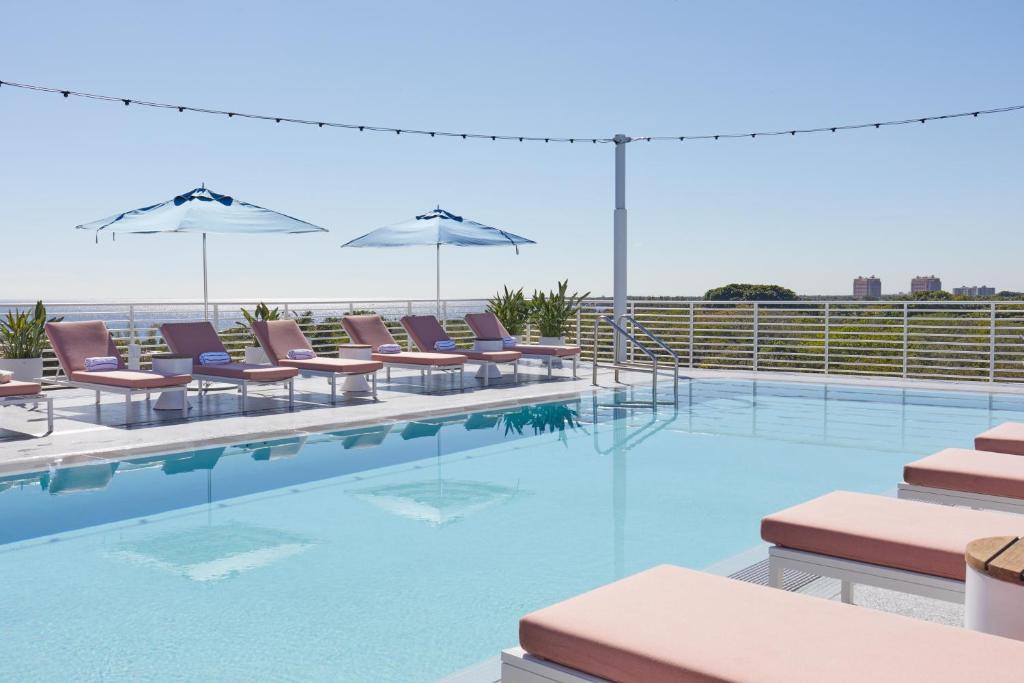 a swimming pool with chairs and umbrellas at Mr C Miami Coconut Grove in Miami