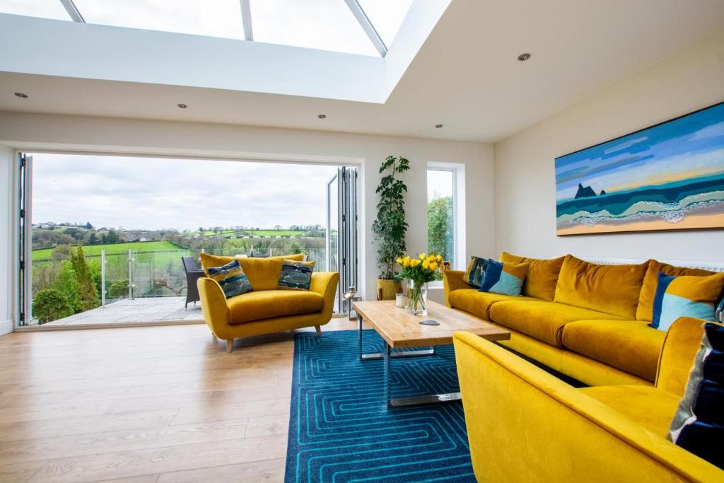 un salon avec des canapés jaunes et un tapis bleu dans l'établissement Sandpiper Cottage, à Saundersfoot