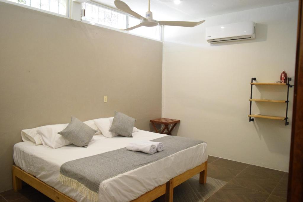 a bedroom with a bed with white sheets and a ceiling fan at Casa Macuil in Brisas de Zicatela