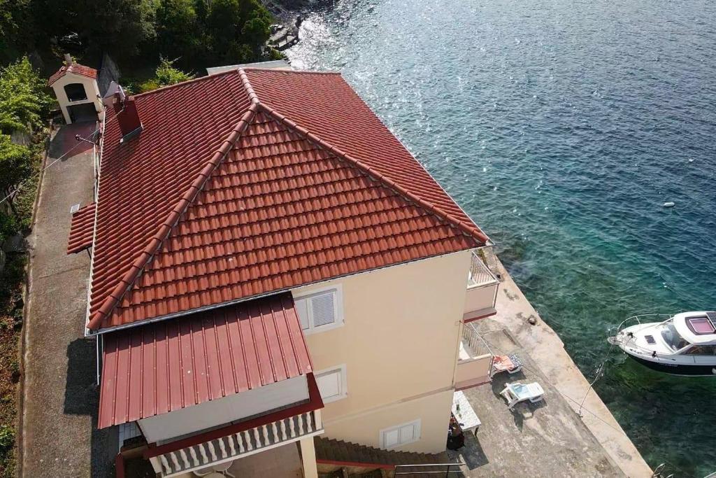 a building with a red roof next to the water at Apartment Savar 8079c in Brbinj