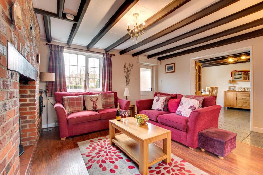 a living room with red furniture and a brick wall at Cherry Garth in Sleights
