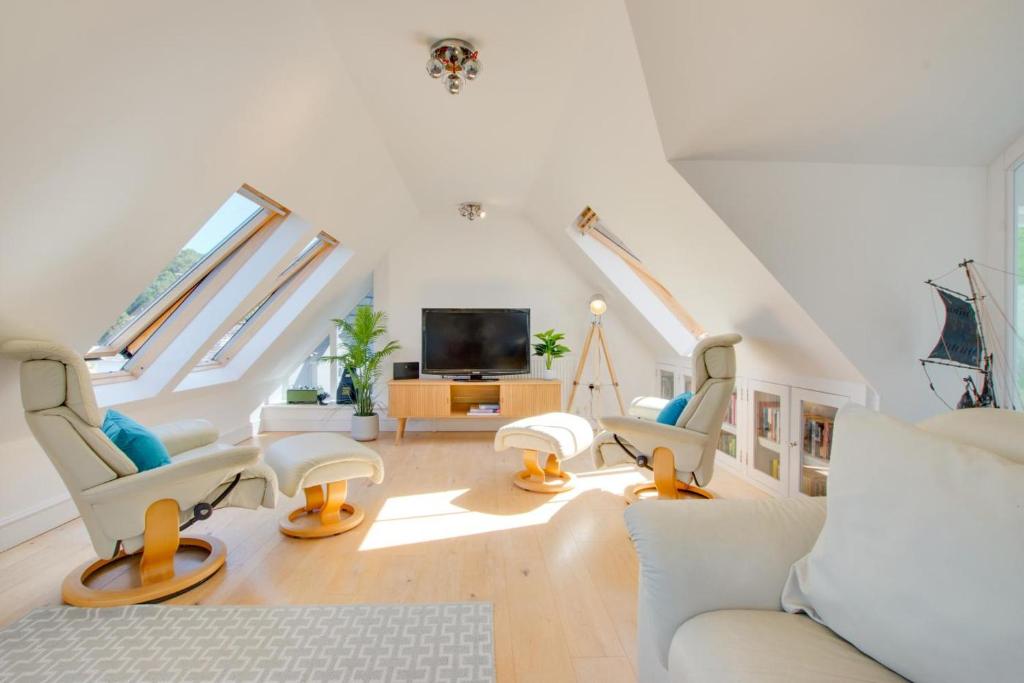 ein Wohnzimmer mit weißen Möbeln und einem Fernseher in der Unterkunft North End House in Fowey