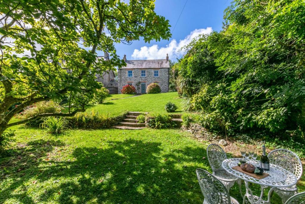 a garden with a table and chairs in front of a house at St Teresas Cottage in Saint Mawgan