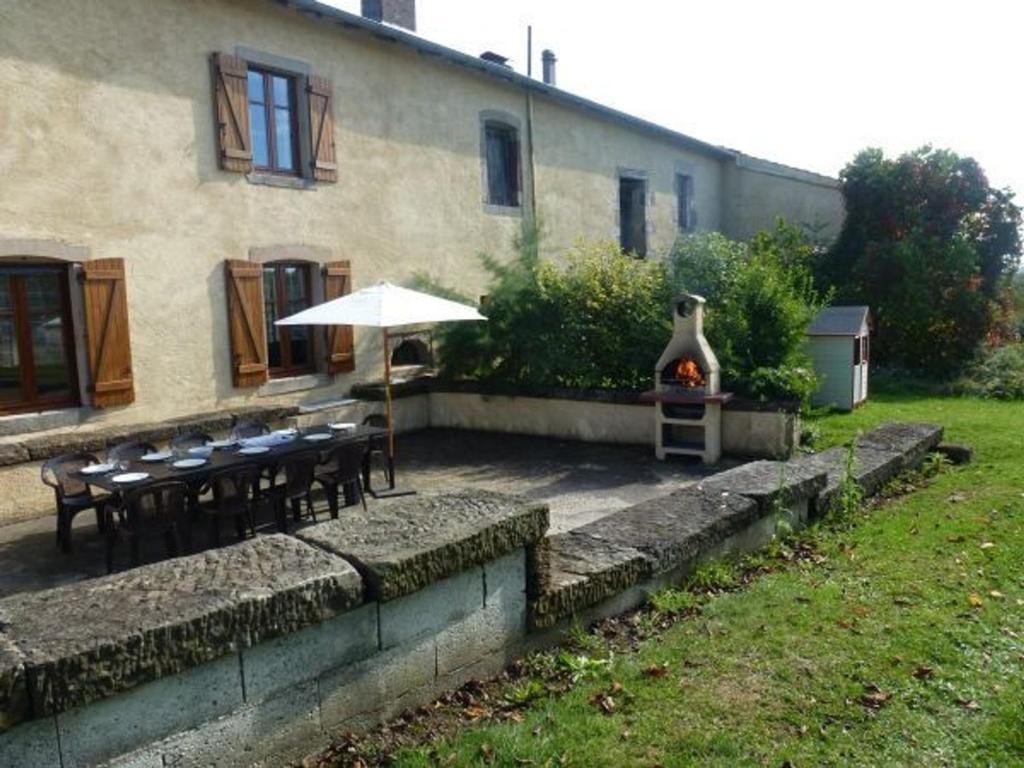 an outdoor patio with tables and an umbrella and a grill at Charmant gîte historique avec terrasse, salle de jeux, et recharge électrique – proche Vittel & Contrexéville - FR-1-589-219 in Serocourt