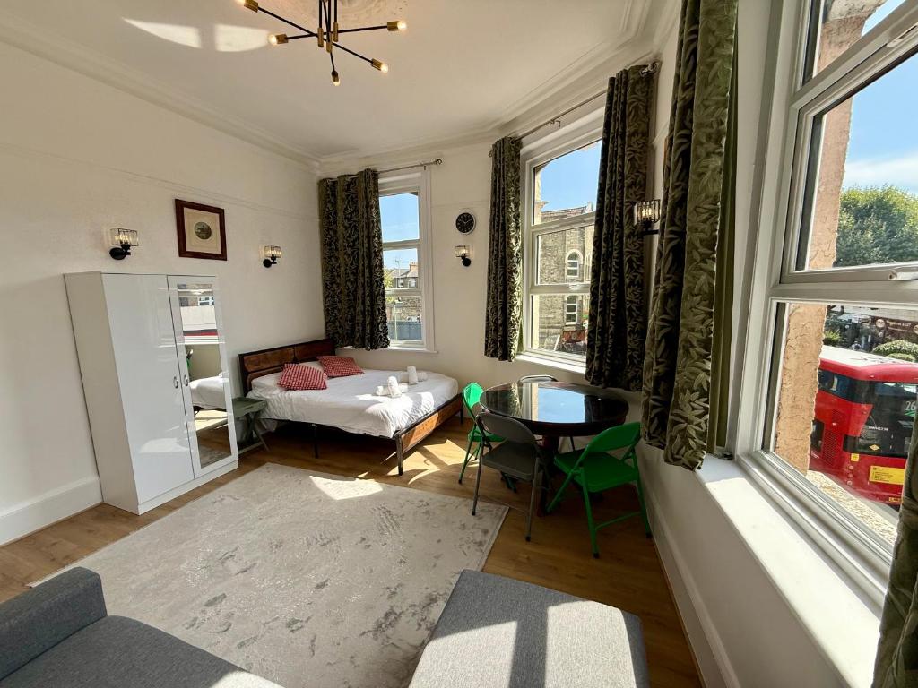 ロンドンにあるThe Finchley Grand Flat Iのベッド、テーブル、窓が備わる客室です。