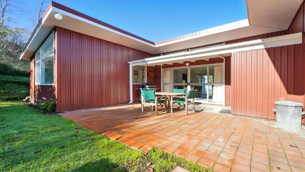 a patio with a table and chairs next to a building at Maison Pierre Rouge - Duvauchelle Holiday Home in Duvauchelle