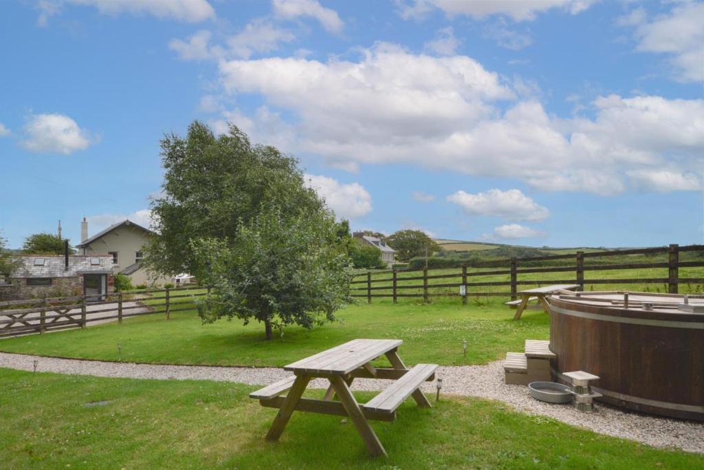 a picnic table and a tub in a field at Higher Treliver Farmhouse in Saint Wenn