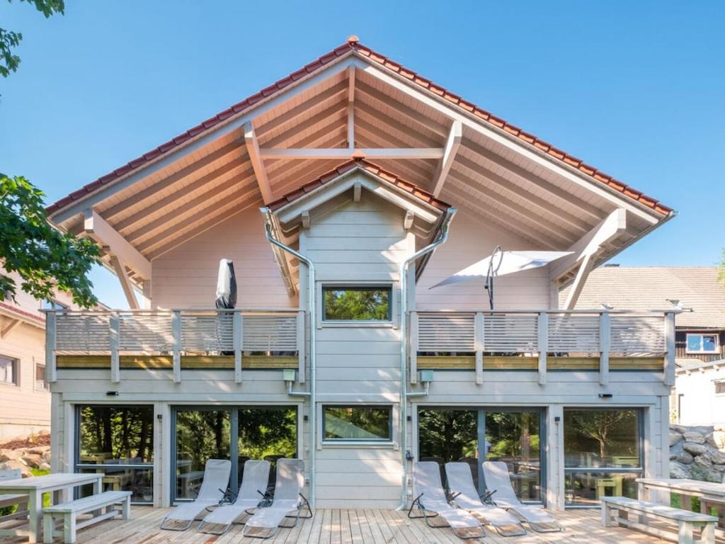 Una casa con una terraza envolvente con sillas. en Bergwaldchalet Wellness 5, en Schierke
