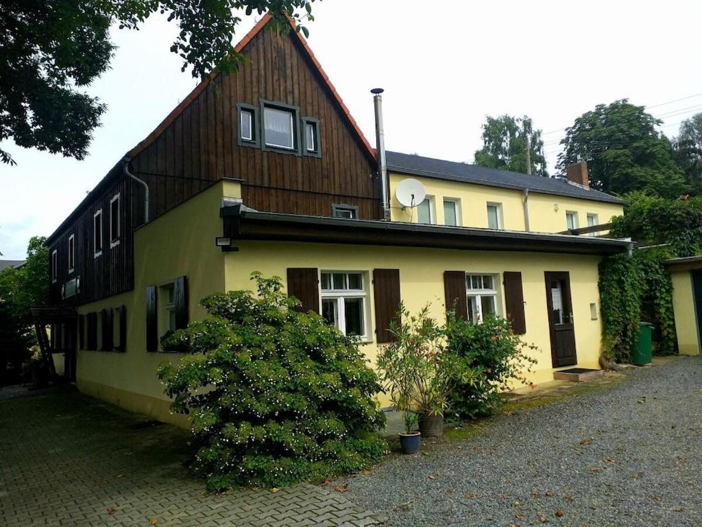 a yellow house with a wooden roof at Holiday home with 2 bedrooms in Naundorf