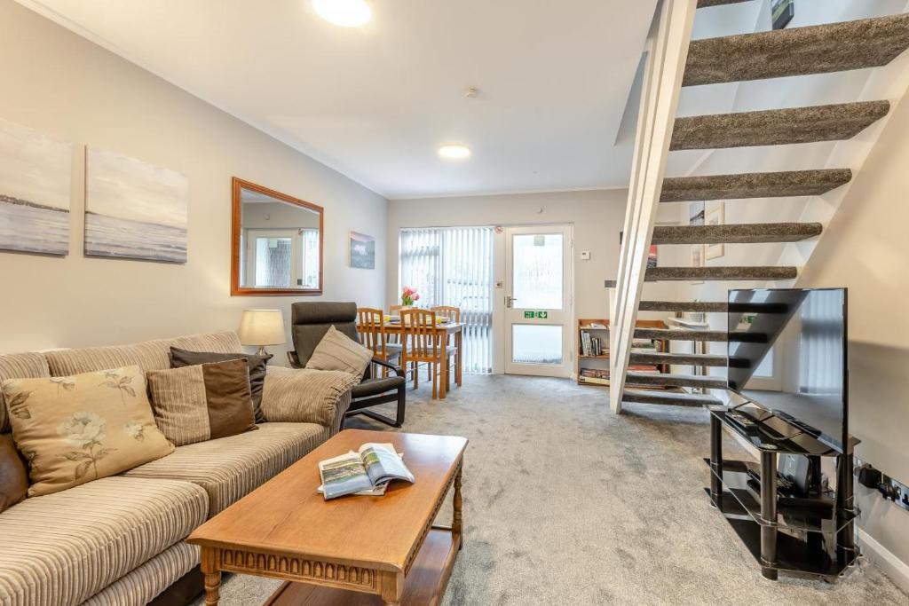 un salon avec un canapé et un escalier dans l'établissement Mews Cottage, à Grasmere