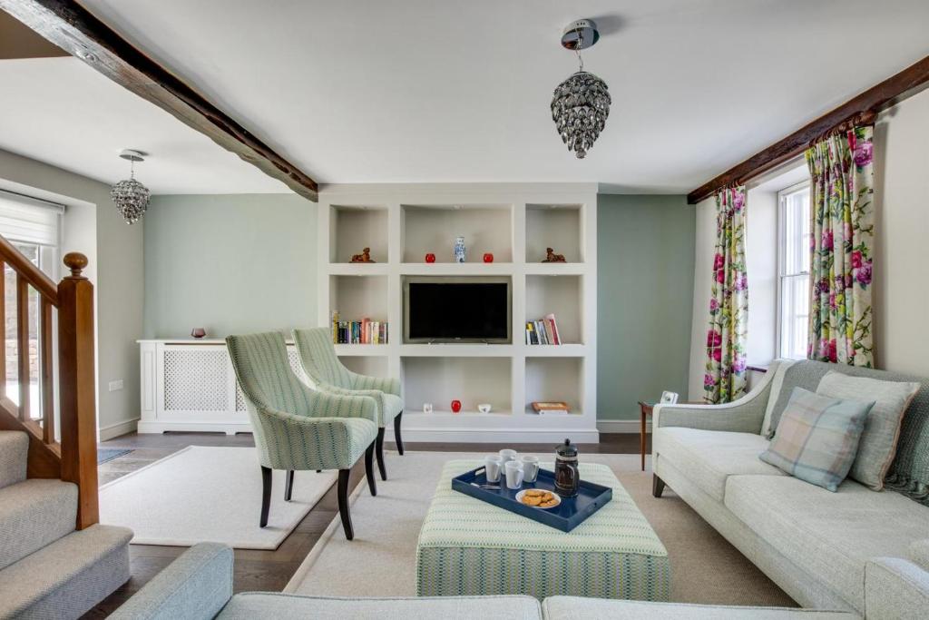 Una sala de estar con un sofá y sillas y un televisor. en Memories Cottage, en Milnthorpe