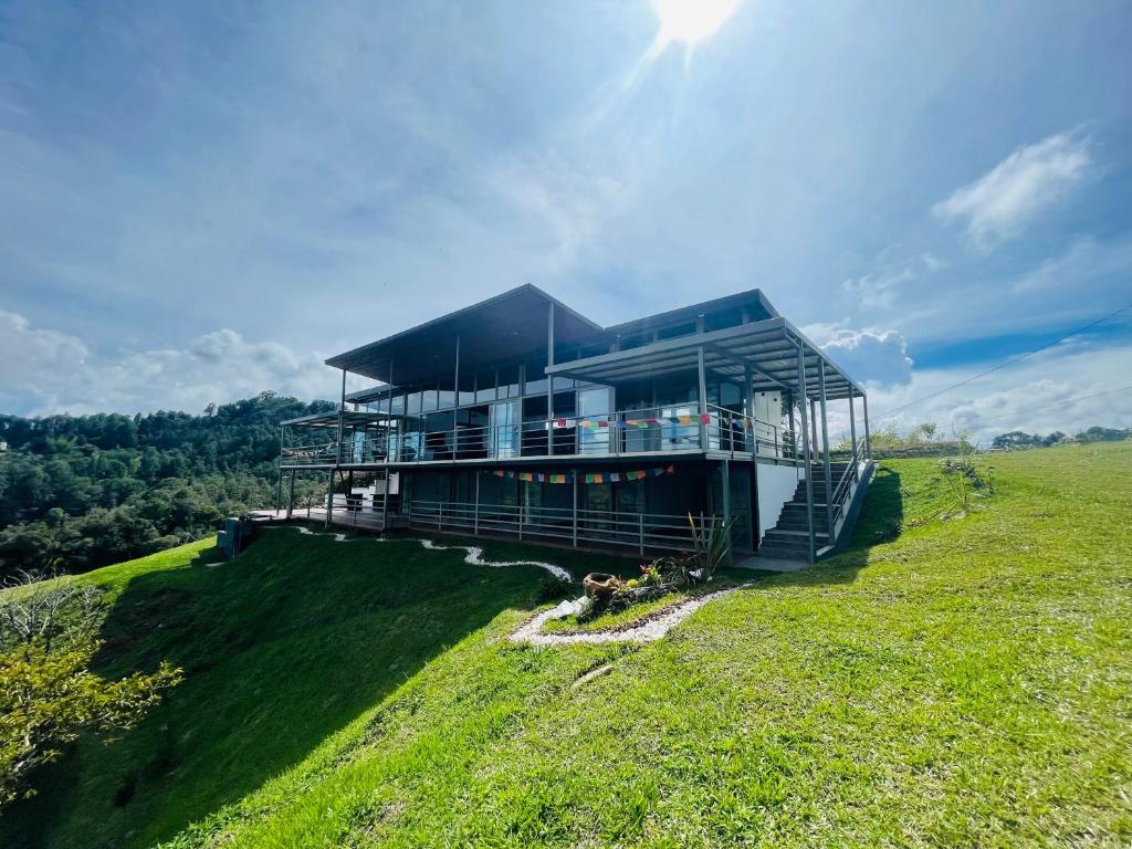 a large building on top of a grassy hill at Casa garuda, hermosa cabaña con vista a la piedra de El Peñol in La Pradera