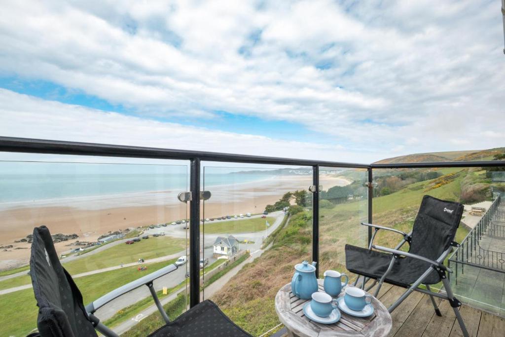 balcón con sillas y mesa y vistas a la playa en Flat 20 Clifton Court, en Croyde