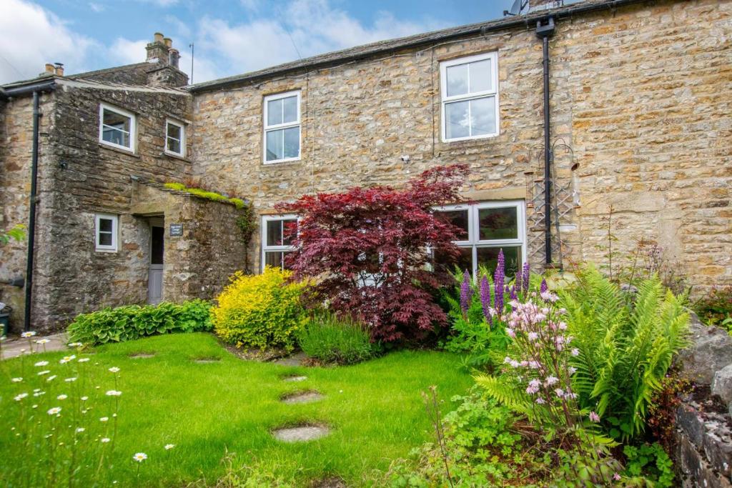 an old brick house with a garden in front of it at High Green Cottage in Low Eskcleth