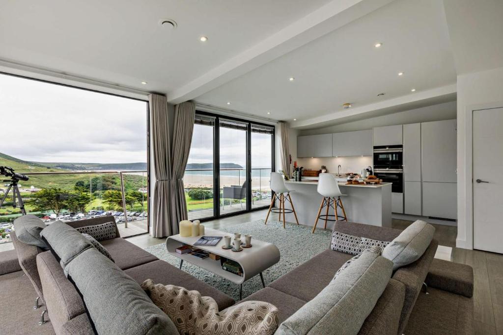a living room with a large couch and a kitchen at Shore End - W1 in Woolacombe